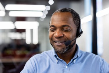 Dost canlısı müşteri hizmetleri temsilcisi modern ofiste kulaklıkla sohbet ediyor. Mesleki davranış, müşteri memnuniyetine olan bağlılığı ve etkili iletişimi yansıtır.