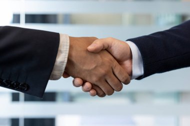 Ortaklık ve anlaşmayı sembolize eden, ofis ortamında güven ve işbirliğini teşvik eden iki iş adamı arasındaki tokalaşma. Başarılı bir anlaşma ve profesyonel bağlantıyı temsil eder.