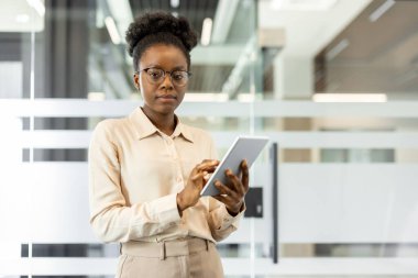 Ofisteki iş kadını iş için tablet kullanıyor. Profesyonel görünüş, dijital görevlere odaklanmış. İş ortamında liderlik, güven ve modern teknoloji kullanımını gösteriyor.