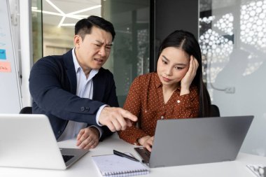 Kızgın bir patron tarafından yönetilen stresli bir çalışanın olduğu ofis sahnesi. Erkek patron dizüstü bilgisayarı işaret ederken, bayan meslektaşı hayal kırıklığına uğramış görünüyor. Kullanılan teknoloji dizüstü bilgisayarları içeriyor, iş stresi