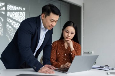 Modern ofiste dizüstü bilgisayar kullanan iş adamları. Odaklanmış takım çalışması işbirliği ve verimliliği ön plana çıkarır. Profesyoneller, erkek ve kadın, inceleme projesi