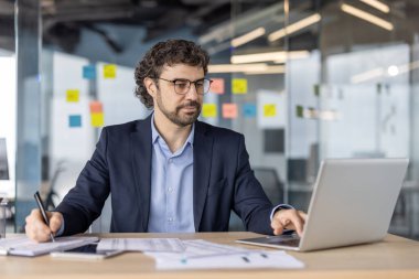 Olgun yatırımcı, evrak işleri ve dizüstü bilgisayar kullanımı ile ilgilenir. Ofis ortamında finansal analiz ve yatırım stratejisine odaklanmış durumda. Mesleki planlama, iş planlamasını ön plana çıkarır