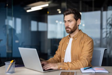 Ofisin içinde dizüstü bilgisayarla çalışan ciddi bir adam, iş adamının klavyede daktilo yazdığını düşünüyor, elektronik rapor hazırlıyor, olgun bir programcı, iş yerinde yeni yazılımlar kodluyor..