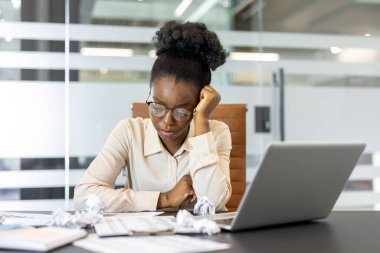 Ofisteki iş kadını, dizüstü bilgisayara ve belgelere bakarken kendini kaybetti. Buruşuk kağıtlar stres, yaratıcılık ya da karar verme yetisini akla getiriyor. Kurumsal çalışma ortamını temsil eder.