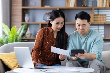 Hesap makinesi ve dizüstü bilgisayarı kullanarak, sorumlu mali planlama, takım çalışması ve işbirliği için bütçe ve gider takibi üzerinde odaklanan çift, evde finans yönetimi.