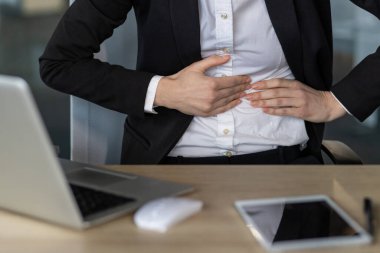 Profesyonel bir iş adamı, masada dizüstü bilgisayar ve tabletle otururken mide ağrısı çekiyor. İş stresi, sağlık sorunları ya da rahatsızlık kavramı. Stres ve acı tasvir edilir