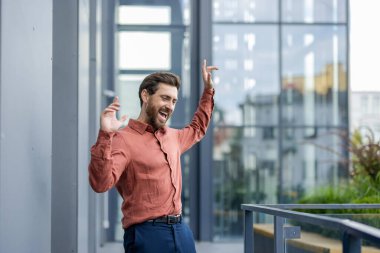 Hedefe ya da başarıya ulaştıktan sonra ofisin yakınında eğlendiğini ifade eden kendine güvenen bir adam. Canlı bir gülüşü olan sıradan bir gömlek giymek, iş dünyası ya da kariyer dönüm noktası coşkusu sergilemek.