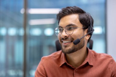 Ofis çağrısı sırasında gülümseyen İspanyol işadamı, modern iş ortamında olumlu iletişim ve profesyonel bağlılığı işaret ediyor.