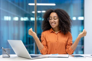 Gülümseyen genç kadın iş sırasında biraz rahatlamak ve dikkat çekmek ister. Ofis masasında dizüstü bilgisayar, telefon ve defterle oturuyor. Huzur, huzur ve denge saçıyor..