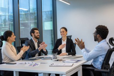 Başarılı bir iş toplantısı sırasında çeşitli profesyonellerin alkışladığı görülüyor. Ofis ayarları takım çalışması, motivasyon ve şirket kültürünü yansıtıyor, işbirliğini vurguluyor.