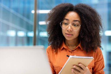 Ofiste kendine güveni tam bir kadın, dikkatle not defterine notlar yazıyor. Profesyonellik, konsantrasyon ve iş konuları için ideal. İş ortamları ve kurumsal sunumlar için mükemmel..