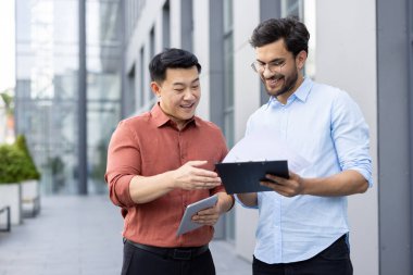 Çağdaş bir şehir ortamında dışarıda duran iki profesyonel evrak işlerini inceliyor. Bir iş dünyasında takım çalışması ve iletişimi ön plana çıkaran bağlı ve işbirlikçi görünürler.