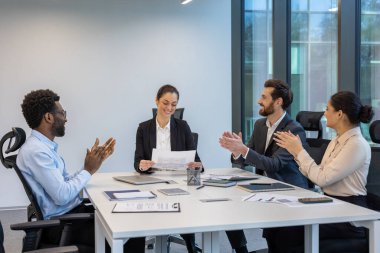 Modern bir ofisteki bir grup iş adamı, ortak bir başarıyı gülümseme ve alkışla kutluyor, takım çalışmasını ve desteğini işbirlikçi bir ortamda geliştiriyor..