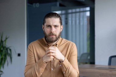 Ofisteki bir masada oturan profesyonel bir birey düşünceli düşüncenin ve profesyonelliğin örneğini veriyor. Görüntü ciddi, odaklanmış ve ticari bir tavır sergiliyor.