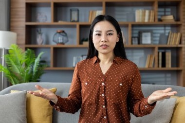 Kendine güveni tam bir Asyalı kadın. Açık açık el kol hareketi yapıyor. Anlayış ve bağlılık ifade ediyor. Kadın, modern estetik ile zahmetsizce harmanlanmış bir şekilde bağlantı duygusunu iletir..