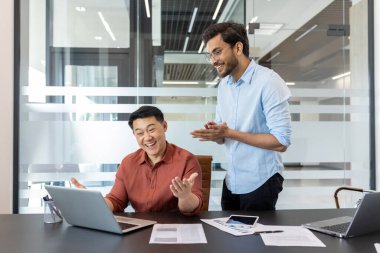 İki iş arkadaşı parlak, modern ofis ortamında, enerjik bir şekilde iş başarısını tartışıp kutlarken görülüyor. Tabloda verimlilik ortamı vurgulanarak grafikler ve akıllı telefon gösteriliyor