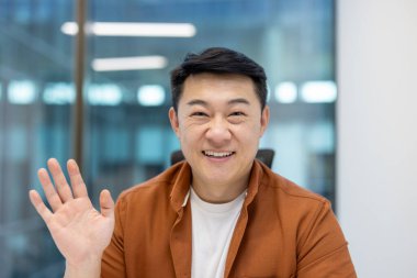 Video görüşmesinde Asyalı yetişkin iş adamı. Kameraya bakarken gerçekten gülümsüyor..