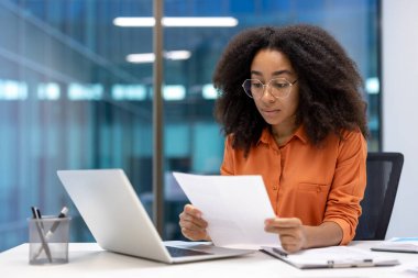 Ofis içinde evrak işleri yapan ciddi kadın muhasebeci, iş kadını sözleşmeleri ve mali raporları kontrol eden vergi formları, belgelerle ve dizüstü bilgisayarla çalışan.