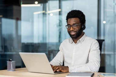 Genç online müşteri destek çalışanı portresi, kulaklıklı adam gülümseyen ve kameraya bakan, memnun ve mutlu yardım hattı çalışanı, çevrimiçi danışman.