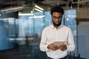 Elinde tablet bilgisayarla ciddi düşünen bir iş adamı. İş kıyafetleri içinde uygulama, e-posta okumak ve finansal verileri İnternet 'te görmek kullanan genç bir adam.