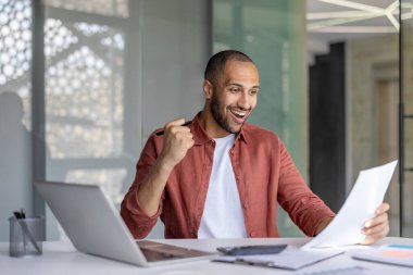 Zaferi ve başarı raporlarını okuyan başarılı bir finansör. Ofisin içinde bilgisayarla çalışan evrak işleriyle uğraşan bir adam, gömlekli bir işadamı kazançlı yatırım sonuçları aldı..