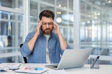 Baş ağrısı, elleriyle yüzünü buruşturan bir adam, ofis içi ofis çalışanı..