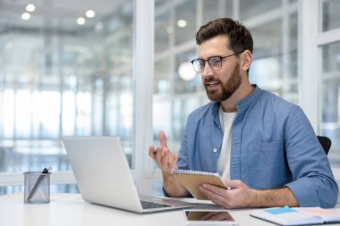 İş yerinde eğitim videosu izleyen adam, ofis çalışanı, not defterine eğitim verileri yazan işadamı, iş yerindeki ciddi iş adamı, video görüşmesi ile ilgili bilgileri netleştirdi.