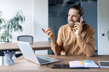 İş dünyasından bir profesyonel bilgisayarlarıyla uğraşırken telefonla iletişim kuruyor. Birey, modern bir ofis ortamında, odaklanma, profesyonellik ve üretkenlik içerir..