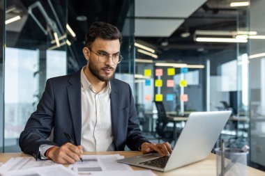 Ofis içinde evrak işleriyle uğraşan ciddi bir iş adamı, vergi formlarını dolduran bir adam, belge ve sözleşme imzalayan bir adam. Başarılı yatırımcı raporunu hazırlıyor..