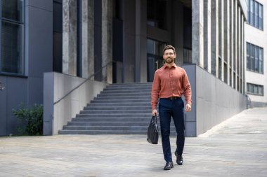Başarılı bir iş adamı elinde bir iş çantasıyla şehirde dolaşıyor. Olgun bir adam ofis binasının dışından mutlu bir şekilde gülümsüyor..
