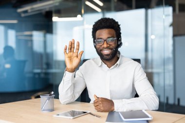 Web kamera görüntüsü, kulaklıklı adam gülümseyen ve kameraya bakan, online iş görüşmesi konferansı. İş adamı ofis içi iş yerinde..