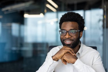 Başarılı hayalperest adam pencereden dışarı yakından bakıyor. İşadamı, ofis içinde çalışmanın, ulaşmanın ve çalışmanın sonuçlarından memnun..