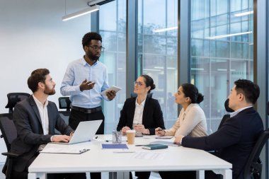 Başarılı bir iş ekibi, bir grup insan iş kadını ve iş adamı konuşuyor ve iş birliği yapıyor, erkek ayakta dururken sunum yapıyor ve bir başlangıç projesi sunuyor.