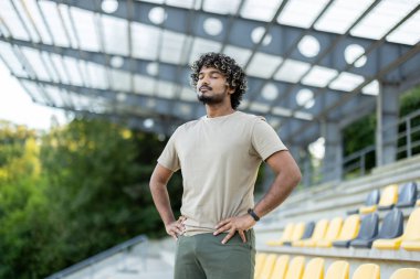 Stadyumda dinlenen sporcu, aktif fiziksel egzersiz ve spor sonrası gözleri kapalı nefes alan bir adam..