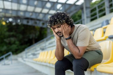 Üzgün adam, aktif fiziksel egzersiz ve zindelikten sonra oturup dinleniyor. Sporcunun şiddetli baş ağrısı ve migreni var..