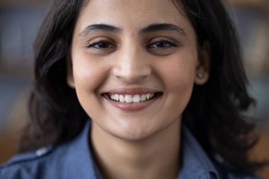 Kameraya gülümseyen kot gömlekli mutlu, esmer, Hintli bir kadının yakın plan portresi..