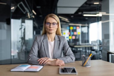 İş yerindeki başarılı, kendine güvenen kadın patron kameraya bakıyor, ciddi ve konsantre. İş kadını iş yerinde ofis içi.