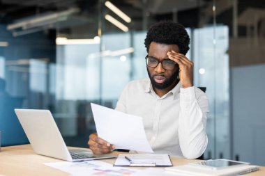 Ofis içi evrak işleriyle uğraşan yorgun ve çok çalışan bir adam. Ofis çalışanı mali rapordan memnun değil. İş adamı elinde belge tutuyor, vergi istatistiksel formu ellerinde.