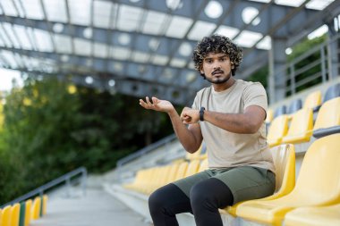 Antrenmanların sonucu yüzünden üzgün ve hoşnutsuz olan sporcu oturur ve dinlenir. Adam verileri bir spor bilekliği ve akıllı bir saatle kontrol ediyor. Hayal kırıklığı içinde kameraya bakıyor..