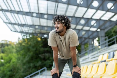 Aşırı yorgun adam derin nefes alıyor, nefes darlığı çekiyor. Sporcu aktif fiziksel egzersiz ve fitness sonrası dinleniyor.
