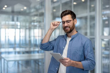 Ofis içinde tablet bilgisayarı olan başarılı genç bir adam. İşadamı çevrimiçi yatırım geliri grafiğini okuyor