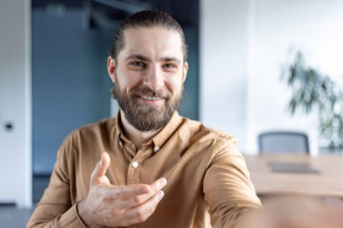 Web kamerası görüntüsü, iş yerindeki adam video görüşmesi için akıllı telefon uygulaması kullanıyor, masa başında otururken iş arkadaşları ve ortaklarla konuşuyor..