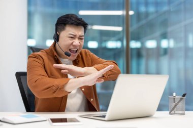 Ofis içinde kulaklıklı kızgın bir adam bağırıyor. Dizüstü bilgisayarı gergin Asyalı bir adam, destek servisi danışmanı..