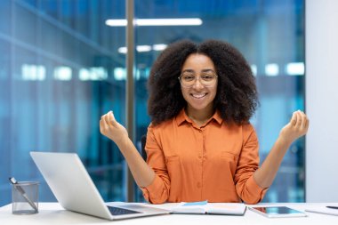 Neşeli iş kadını iş yerinde dinleniyor ve dinleniyor. Masada Lotus pozisyonunda gülümseyen ve kameraya bakan bir kadın.