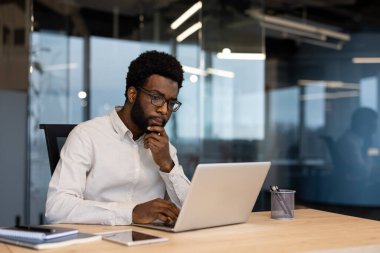 Ofisin içinde dizüstü bilgisayarla çalışan ciddi bir iş adamı. Gömlekli adam yoğunlaşmış, elektronik mali rapor hazırlıyor..