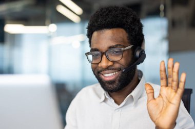 Video görüşmesi sırasında kulaklığı olan neşeli bir profesyonel, dostça çevrimiçi iletişim sergiliyor.