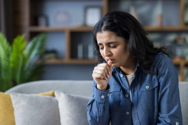 Genç Hintli kadın oturma odasındaki kanepede otururken grip ya da virüs belirtileri gösteriyor..