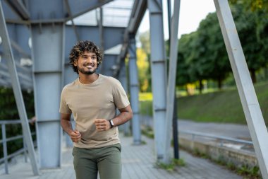 Genç bir adam spor kıyafetleri içinde koşuyor ve aktif fiziksel egzersizler yapıyor..