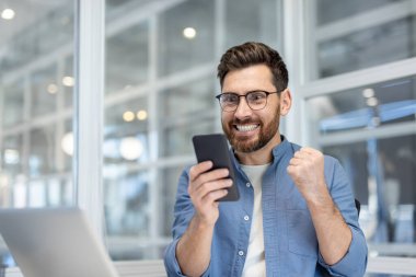 Elinde telefonla zaferi kutlayan ve başarı elde eden bir adam. Şirket çalışanı kazanmakla ilgili online uyarı mesajı almış. Akıllı telefon kullanan bir iş adamı.