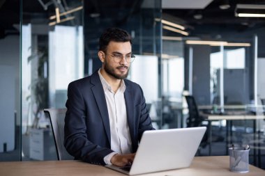 Ofis içinde dizüstü bilgisayarla çalışan ciddi bir iş adamı. Takım elbiseli bir adam masa başında oturmuş klavyeyle yazı yazıyor, geç saatlere kadar çalışıyor..
